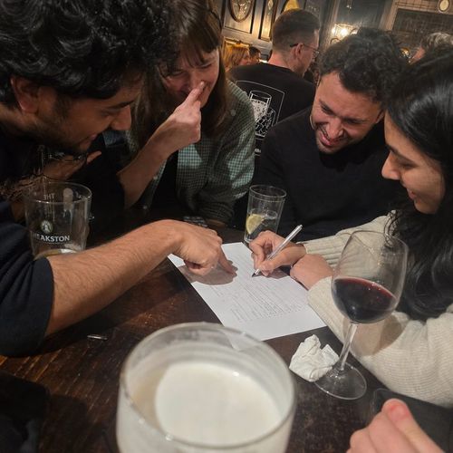 Flash photo of a quiz team huddled over the answer sheet